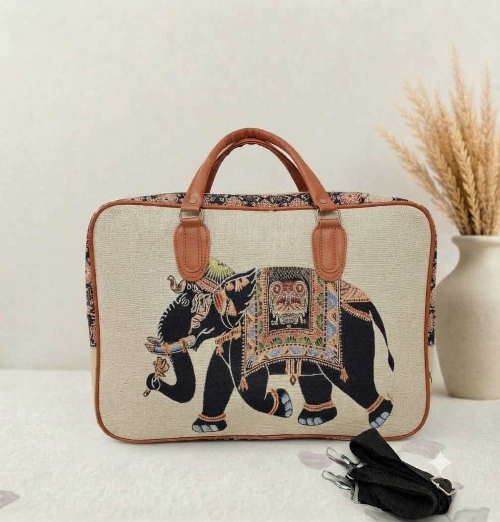 A structured canvas travel duffle bag featuring a detailed traditional Indian royal elephant motif, accented with brown top handles and complete with a detachable shoulder strap.