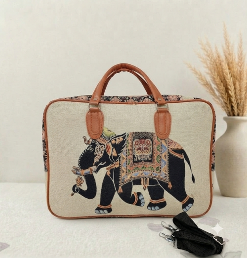 A structured canvas travel duffle bag featuring a detailed traditional Indian royal elephant motif, accented with brown top handles and complete with a detachable shoulder strap.