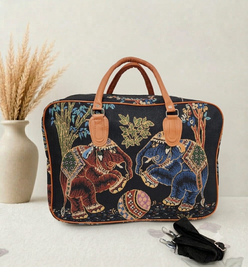A structured canvas travel duffle bag featuring a detailed traditional Indian royal elephant motif, accented with brown top handles and complete with a detachable shoulder strap.
