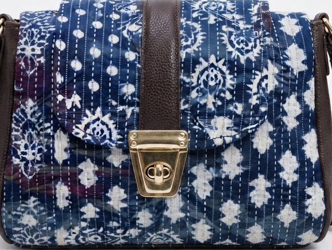 A textured crossbody sling bag featuring a vibrant multicolor front panel, shown open to display two top zipper sections and an adjustable shoulder strap.