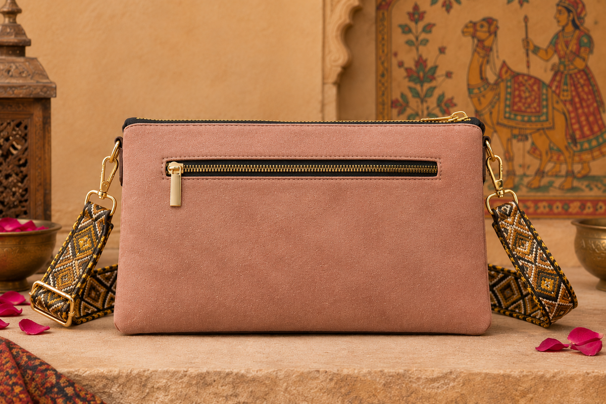 A suede multi-pocket sling bag with a circular embossed center emblem and an adjustable patterned crossbody strap.