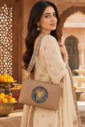 A suede multi-pocket sling bag with a circular embossed center emblem and an adjustable patterned crossbody strap.
