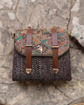 An overhead view showing the open interior of a beige straw-woven crossbody sling bag, revealing a dark brown fabric lining divided into two main sections by a central zippered compartment.