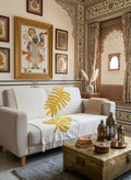 The Mustard Palm Leaf Tufted Sofa Throw featuring a raised tropical leaf pattern, textured cotton fabric, and fringed edges on a cozy living room couch.