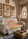 A cream cotton sofa throw blanket featuring a raised, textured tufted rising sun pattern styled on a living room couch.
